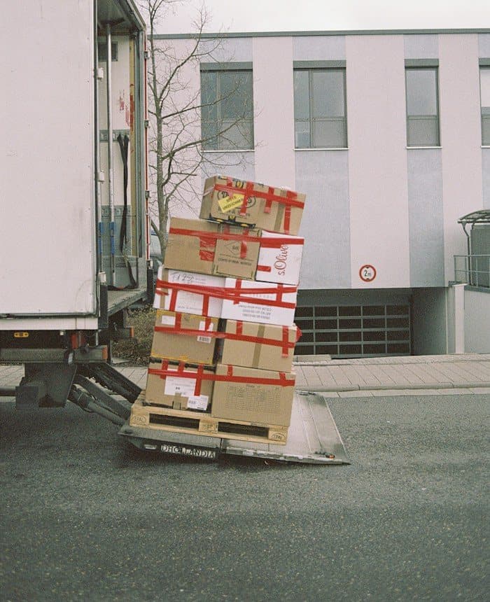 Securely taped cartons on a trolley beside a truck, ready to go into storage