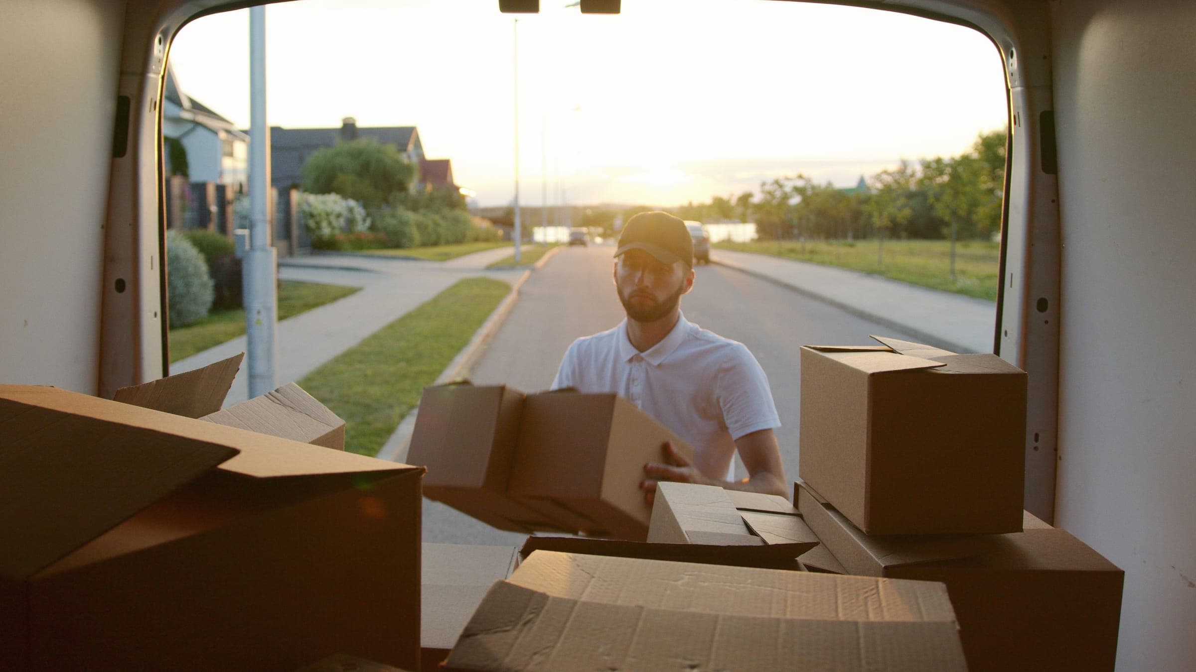 Mover loading cardboard cartons into a van packed for a house shift